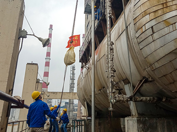 5月10日中午，在動力車間三期工藝除氧器地面，黨員突擊隊隊員用滑輪往工藝除氧器平臺運送鋼絲網(wǎng)，用以纏繞新填料.jpg